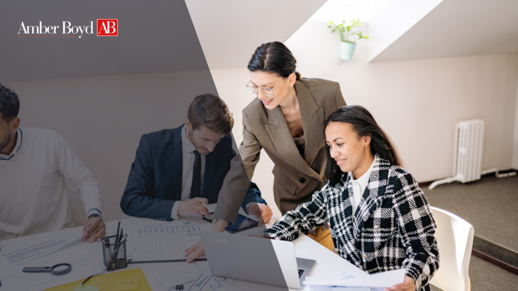 Law firm team collaborating around a table with documents and a laptop; Amber Boyd AB logo in the top-left corner.