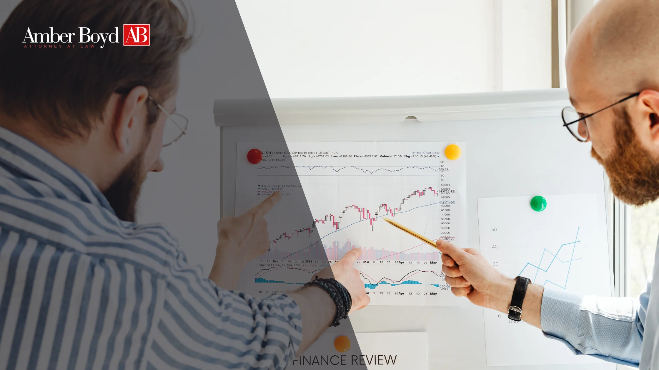 Two professionals review a printed financial chart pinned to a board, pointing at data during a discussion.