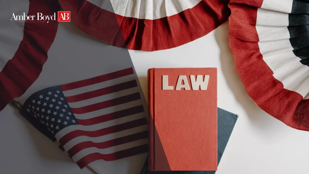 Patriotic law-themed image with a red LAW book, an American flag, and red-white-blue fabric beside the Amber Boyd branding logo in the corner.