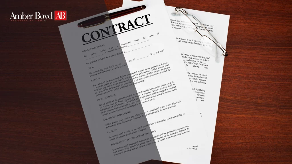 Contract documents on a dark wood desk with a burgundy pen, glasses, and Amber Boyd AB branding in the corner.