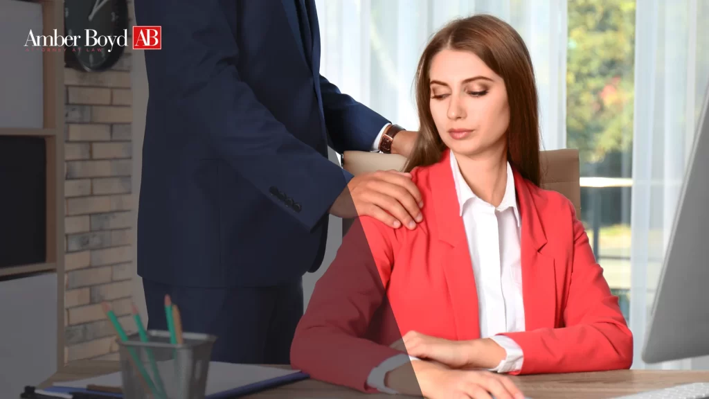0611 What Is Sexual Harassment Under Indiana Law_ A Practical Guide - Amber Boy - Amber Boy Woman in a red blazer sits at a desk while a man in a navy suit rests his hand on her shoulder; Amber Boyd AB logo in the top-left corner.