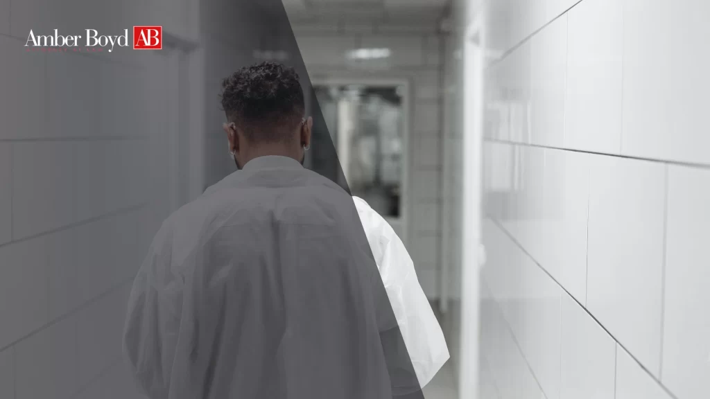 Person seen from behind wearing a white shirt, walking down a tiled hallway with a dark overlay and Amber Boyd AB logo in the top-left corner.