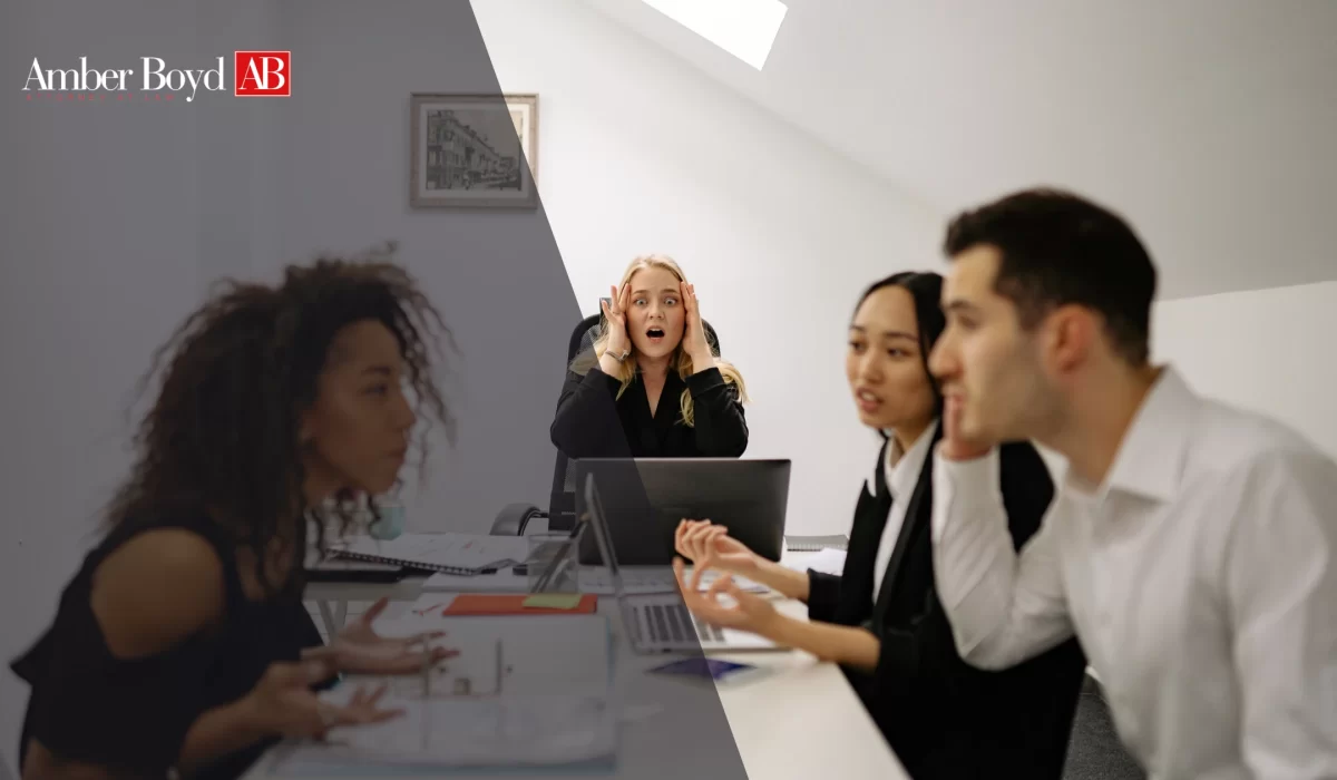 Team of colleagues in a business meeting around a table; the woman in the center has a surprised expression, hands to her head.
