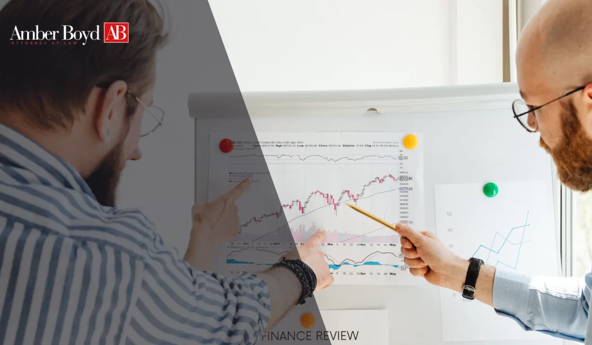Two professionals review a printed financial chart pinned to a board, pointing at data during a discussion.