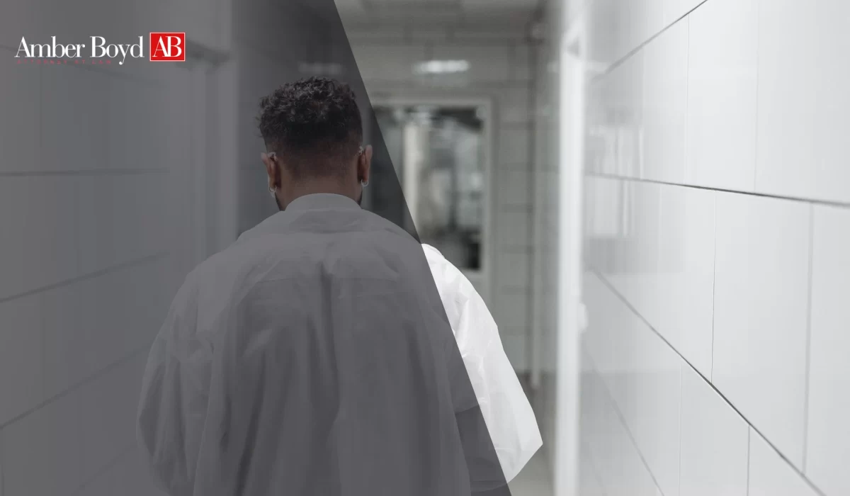 Person seen from behind wearing a white shirt, walking down a tiled hallway with a dark overlay and Amber Boyd AB logo in the top-left corner.
